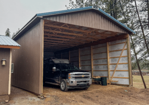 A 26x48x14 Open-Ended RV Storage Residential Pole Barn, Featuring Desert Brown metal siding, with Hawaiian Blue metal roofing, Built By MQS in Bonner, MT