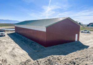 A 40x100x14 Hay and Ag Equipment Storage, featuring rural red metal siding, and medium green metal roofing, with sidelight, Built By MQS in Kalispell, MT