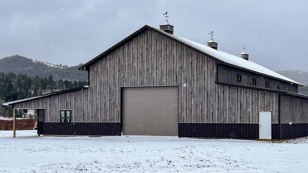 A 40x100x20 Multi-Stall Monitor Horse Barn, featuring Distressed Gray Barnwood Metal Siding, and Krinkle Burnished slate Trim and Roofing, available for custom build and ready for heavy weather in MT