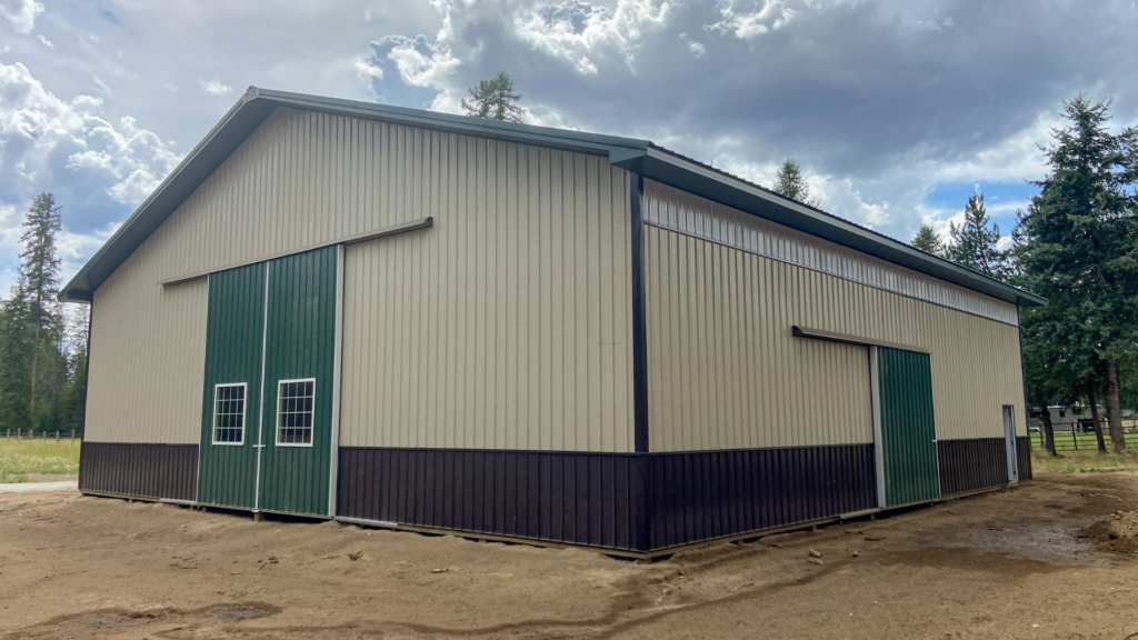 A 60x60x16 engineered clear-span Indoor Riding Arena, featuring Tan Metal Siding, Evergreen Metal Wainscoting and Roofing, available for custom build by MQS in MT