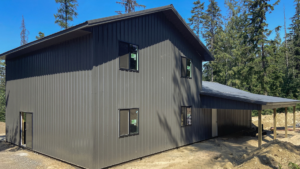 Rear of a 24x32x10 Pole Barn Garage attaching to 28x32x18 Barndominium Shell, featuring Dark Grey Metal Siding, Built by MQS, in Bayview, ID